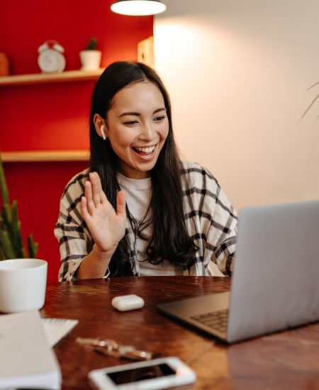 Positive girl in wireless headphones speaks by video link in laptop Positive girl in wireless headphones speaks by video link in laptop